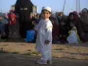 A Palestinian boy wearing a traditional uniform stands in front of Muslim women performing Eid al-Fitr prayers, marking the end of the holy fasting month of Ramadan, in Eastern Gaza City on Friday.