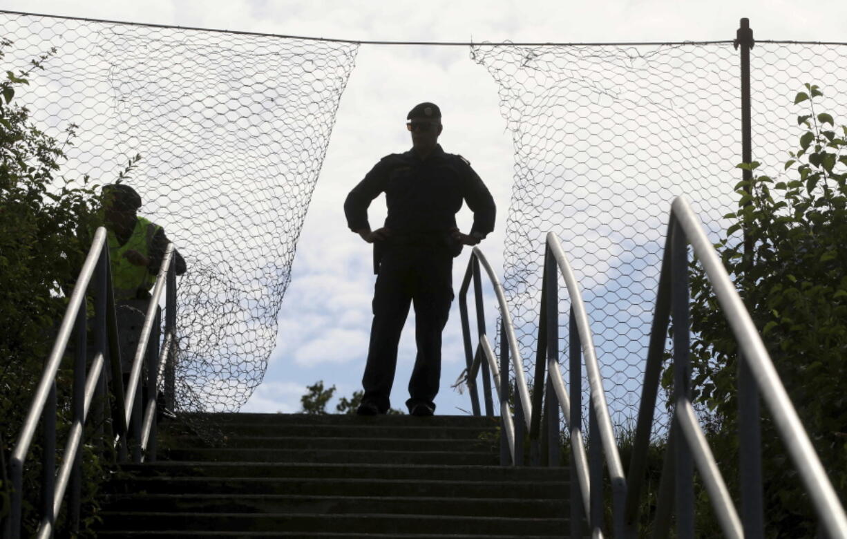 A police officer is silhouetted when standing in the gap of a fence when Austrian police practice the protection of the border fence between Slovenia and Austria in Spielfeld, Austria, Tuesday, June 26, 2018.