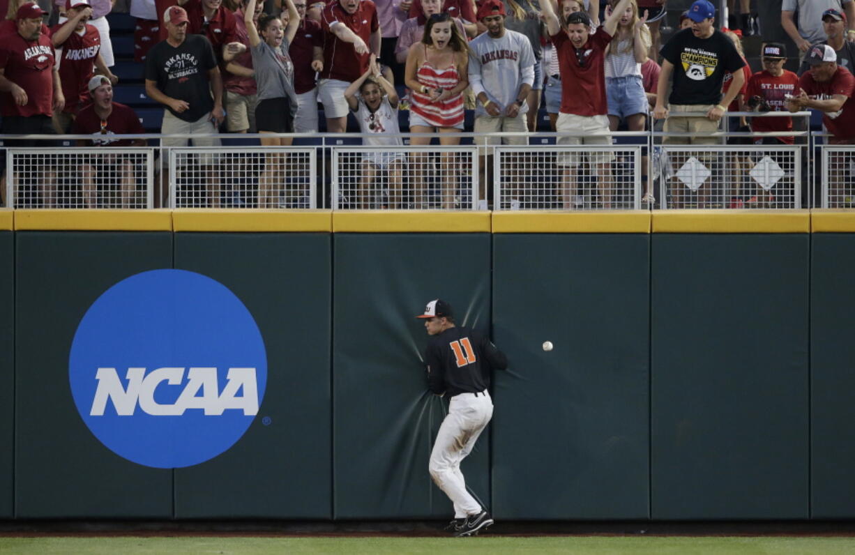 Oregon State right fielder Trevor Larnach (11) hits the wall on a double by Arkansas’ Dominic Fletcher during the seventh inning of Game 1 of the NCAA College World Series baseball finals in Omaha, Neb., Tuesday. Arkansas won 4-1 to take the lead in the best-of-three series.