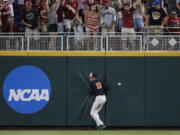 Oregon State right fielder Trevor Larnach (11) hits the wall on a double by Arkansas’ Dominic Fletcher during the seventh inning of Game 1 of the NCAA College World Series baseball finals in Omaha, Neb., Tuesday. Arkansas won 4-1 to take the lead in the best-of-three series.