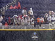 Spectators wait in the rain during a rain delay before Game 1 of the NCAA College World Series baseball finals between Oregon State and Arkansas, in Omaha, Neb in Omaha, Neb., Monday, June 25, 2018. Game 1 has been rescheduled for Tuesday.