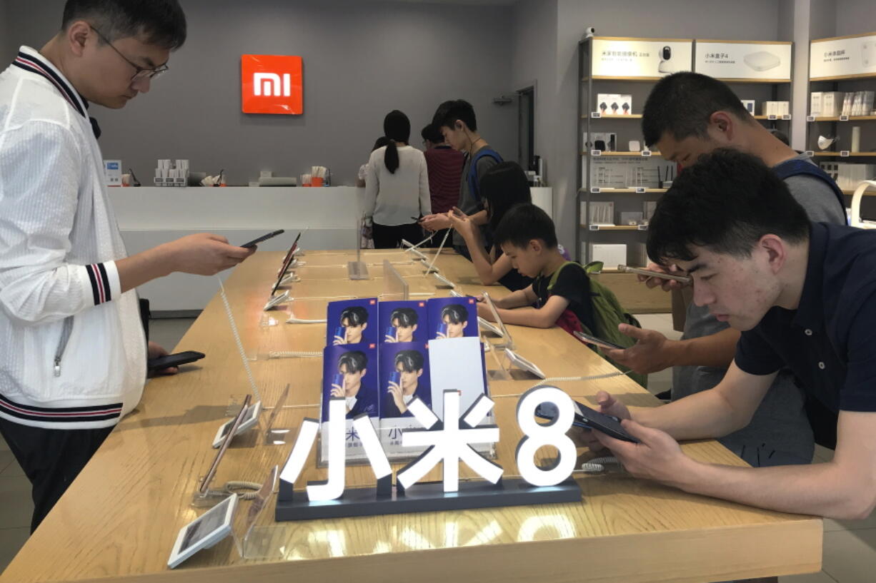 In this Wednesday, June 20, 2018, photo, People try out the Xiaomi latest smartphones on display at the Xiaomi store in Beijing, Wednesday, June 20, 2018. Xiaomi, a Chinese startup that helped to pioneer the trend toward ultra-low-priced smartphones, is preparing for what would be the biggest initial public offering since e-commerce giant Alibaba’s in 2014. The 8-year-old is a star among the Chinese unicorns, a term that refers to startup companies that are valued at more than $1 billion. It has a dedicated Chinese fan base and its media-savvy leader is an Asian celebrity. But it is untested outside the region.