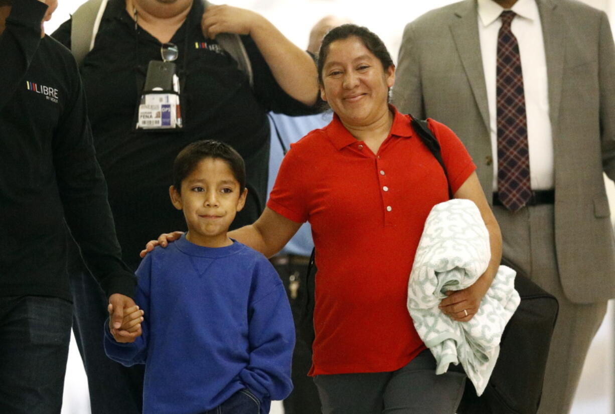 Darwin Micheal Mejia, left, and his mother Beata Mariana de Jesus Mejia-Mejia are escorted to a news conference after their reunion at Baltimore-Washington International Thurgood Marshall Airport, Friday, June 22, 2018, in Linthicum, Md. The Justice Department agreed to release Mejia-Mejia’s son after she sued the U.S. government in order to be reunited following their separation at the U.S. border. She has filed for political asylum in the U.S. following a trek from Guatemala.