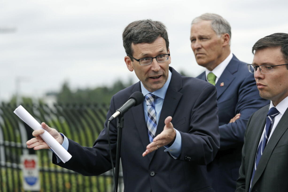 In this June 21, 2018, file photo, Attorney General Bob Ferguson, left, speaks as Washington Gov. Jay Inslee, center, and Solicitor General Noah Purcell look on at a news conference announcing a lawsuit against the Trump administration over a policy of separating immigrant families illegally entering the United States, in front of the Federal Detention Center in SeaTac, Wash. Seventeen states, including Washington, New York and California, are suing to force the Trump administration to reunite migrant families who have been separated at the U.S.-Mexico border. The lawsuit filed Tuesday, June 26, 2018, is the first by states over the practice.