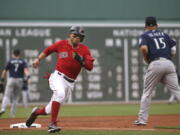 Boston Red Sox's Mookie Betts rounds third past Seattle Mariners third baseman Kyle Seager (15) to score on a double by J.D. Martinez in the first inning of a baseball game at Fenway Park, Friday, June 22, 2018, in Boston.