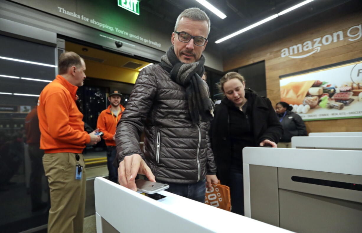 FILE- In this Jan. 22, 2018, file photo a customer scans his Amazon Go cellphone app at the entrance as he heads into an Amazon Go store in Seattle. Microsoft is working on automated checkout technology that could help retailers compete with Amazon’s new cashier-less stores. One firm building automated checkout systems, AVA Retail, said Thursday, June 14 that it is working with Microsoft on the technology for physical stores.