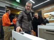 FILE- In this Jan. 22, 2018, file photo a customer scans his Amazon Go cellphone app at the entrance as he heads into an Amazon Go store in Seattle. Microsoft is working on automated checkout technology that could help retailers compete with Amazon’s new cashier-less stores. One firm building automated checkout systems, AVA Retail, said Thursday, June 14 that it is working with Microsoft on the technology for physical stores.