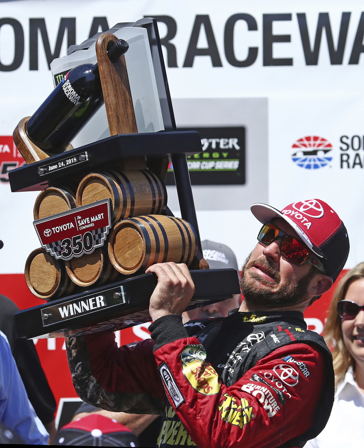 Martin Truex Jr. raises the trophy after winning a NASCAR Sprint Cup Series auto race Sunday, June 24, 2018, in Sonoma, Calif.