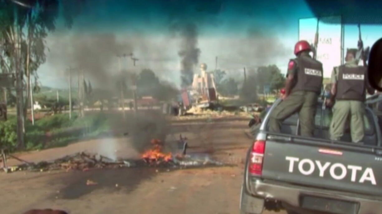 A bonfire and overturned vehicles block the road as police attempt to restore calm Sunday in the town of Jos, Nigeria. Scores of people have reportedly died in weekend clashes in central Nigeria between mostly Muslim herders and Christian farmers.