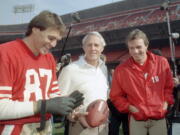 San Francisco 49ers’ head coach Bill Walsh, center, laughs with quarterback Joe Montana (16) and receiver Dwight Clark, left, at San Francisco’s Candlestick Park in this 1985 photo. Clark, the former 49ers wide receiver whose reception known as “The Catch” sent San Francisco to its first Super Bowl, has died one year after revealing he had ALS. He was 61. The team said Clark died Monday, June 4, 2018, surrounded by friends and family.