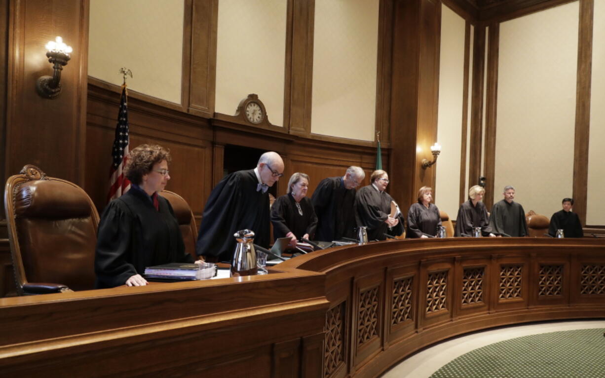 The justices of the Washington Supreme Court take their seats on Thursday at the start of a session where they were scheduled to hear arguments in Olympia over whether state lawmakers acted constitutionally when they passed a new state law designed to improve police training in de-escalation tactics and make it easier to prosecute officers for negligent shootings. (Ted S.