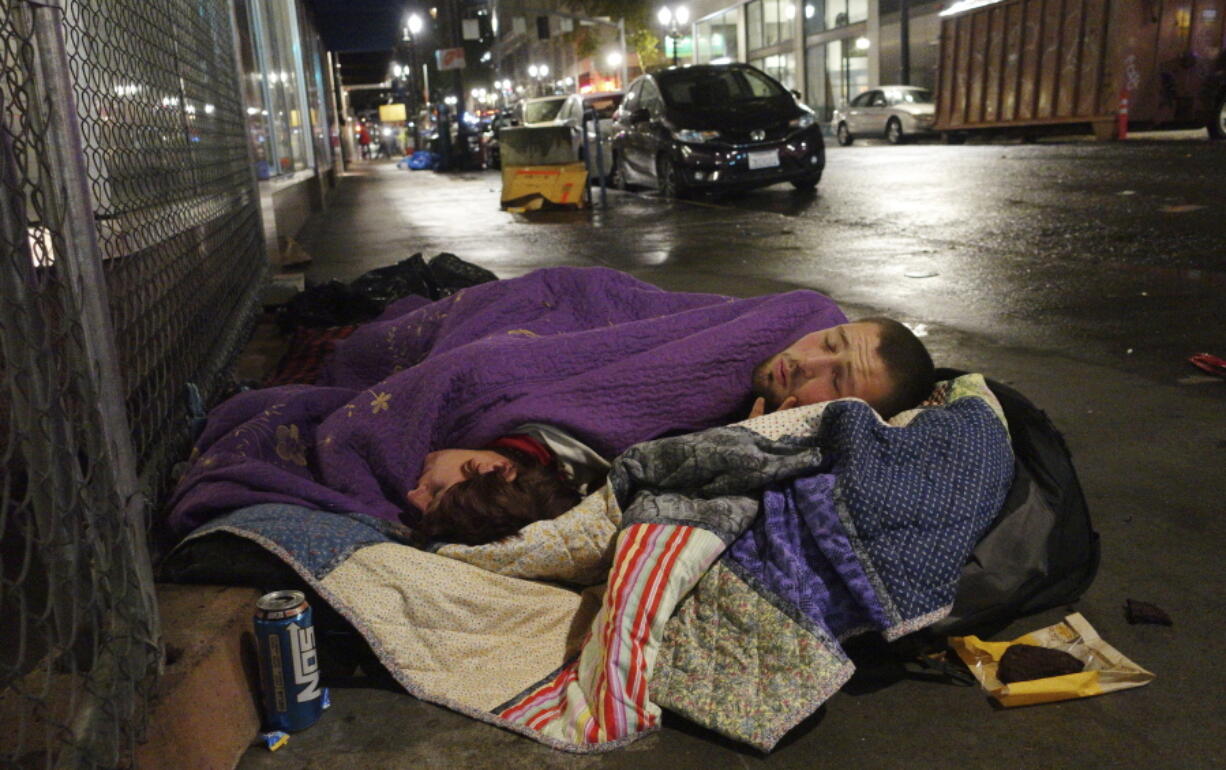 Taz Harrington, right, sleeps with his girlfriend, Melissa Ann Whitehead, on a street Sept. 18, 2017, in downtown Portland.