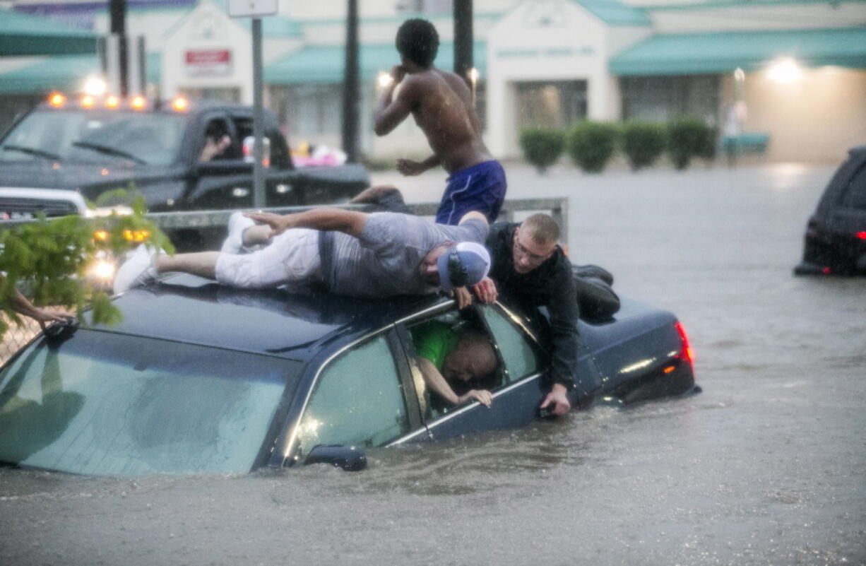 Mark Pickett, left, and Ryan Craig, right, work to rescue Bruce Salley, who was trapped in his car by flood waters in a supermarket parking in Rockford, Ill. An evening thunderstorm brought heavy rains across the Rock River Valley causing vehicles to get stuck in flood waters and stranding motorists.