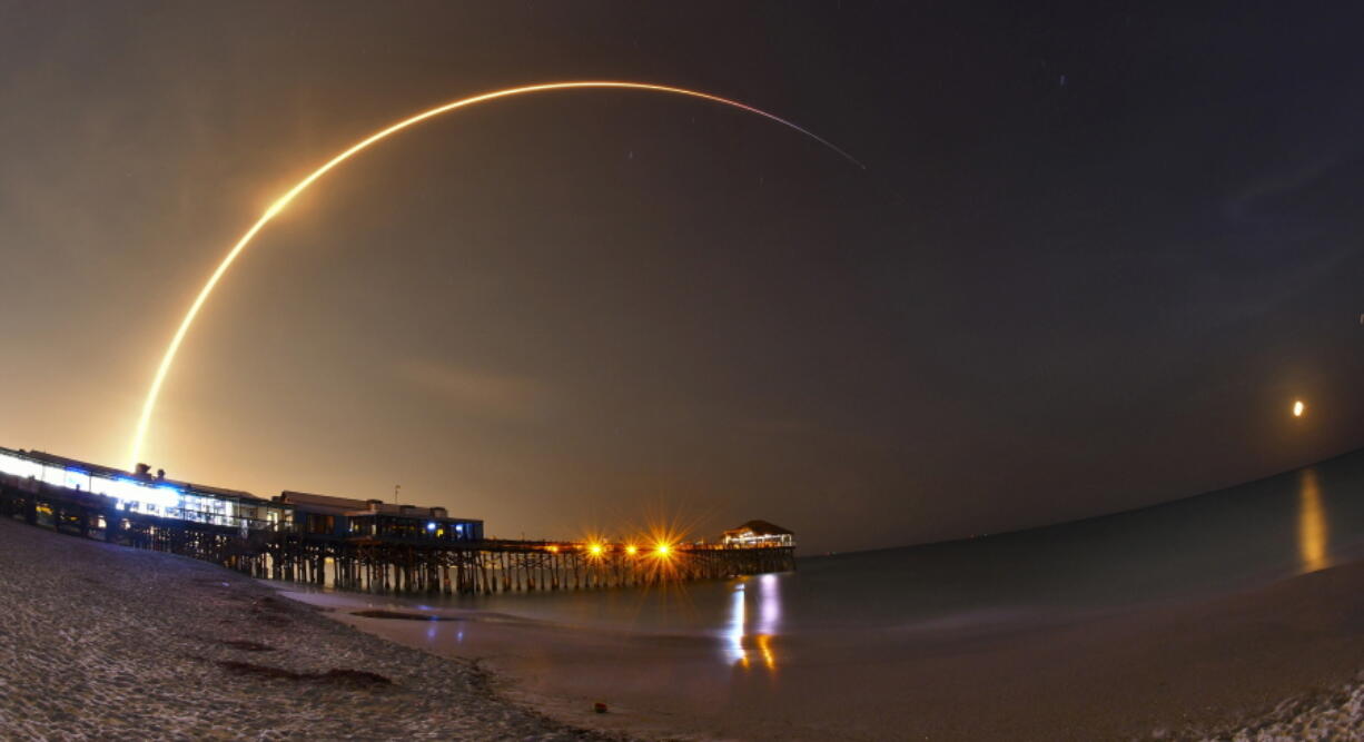 A SpaceX Falcon 9 rocket lifts off from Cape Canaveral Air Force Station with the SES-12 commercial communications satellite in Cape Canaveral, Fla., on Monday. The rocket launched at 12:45 a.m. Monday morning with a satellite bound for geostationary orbit. A long exposure with a wide angle lens of the launch shows the rocket rising over the Cocoa Beach Pier in the foreground, and the waning gibbous moon rising in the east.