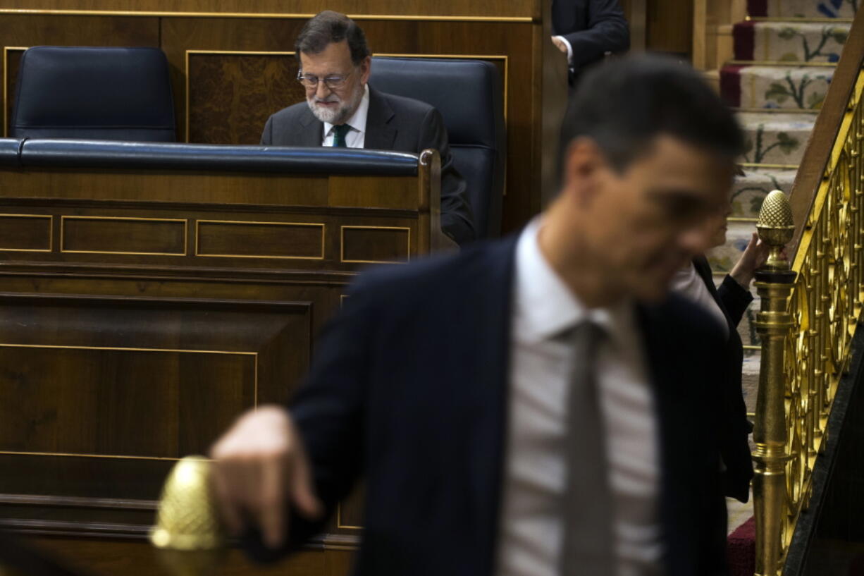 Spain’s Socialist leader Pedro Sanchez, unfocused right, walks past Spain’s Prime Minister Mariano Rajoy, background left, during the first day of a motion of no confidence session at the Spanish parliament in Madrid, Thursday, May 31, 2018. Spain’s opposition Socialists tried to persuade smaller parties to support their bid to oust Prime Minister Mariano Rajoy’s conservative government as they opened a tense parliamentary debate on their no-confidence motion.