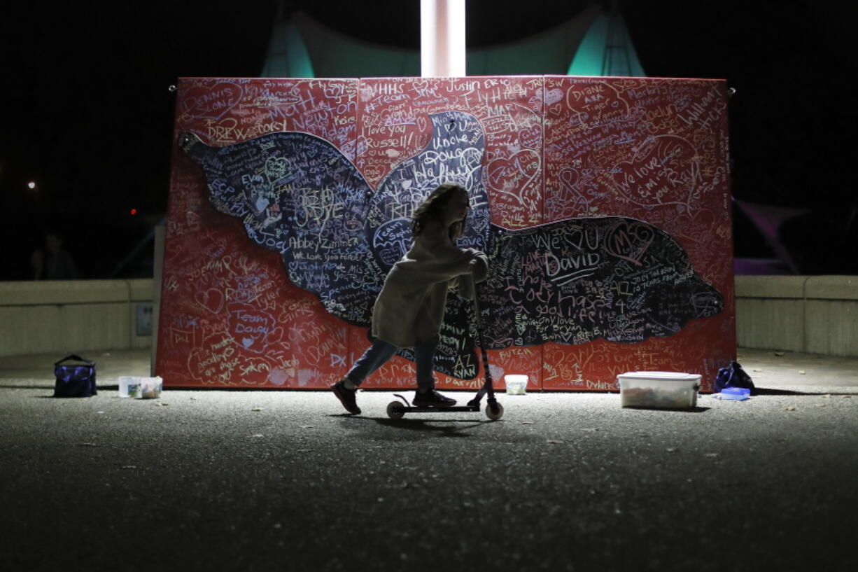 A child plays beside a message board adorned with notes for loved ones who took their own lives during an Out of the Darkness Walk event organized by the Cincinnati Chapter of the American Foundation for Suicide Prevention at Sawyer Point Park in Cincinnati, on Oct. 15, 2017. Suicide rates inched up in nearly every U.S. state from 1999 through 2016, according to a new government report released Thursday.