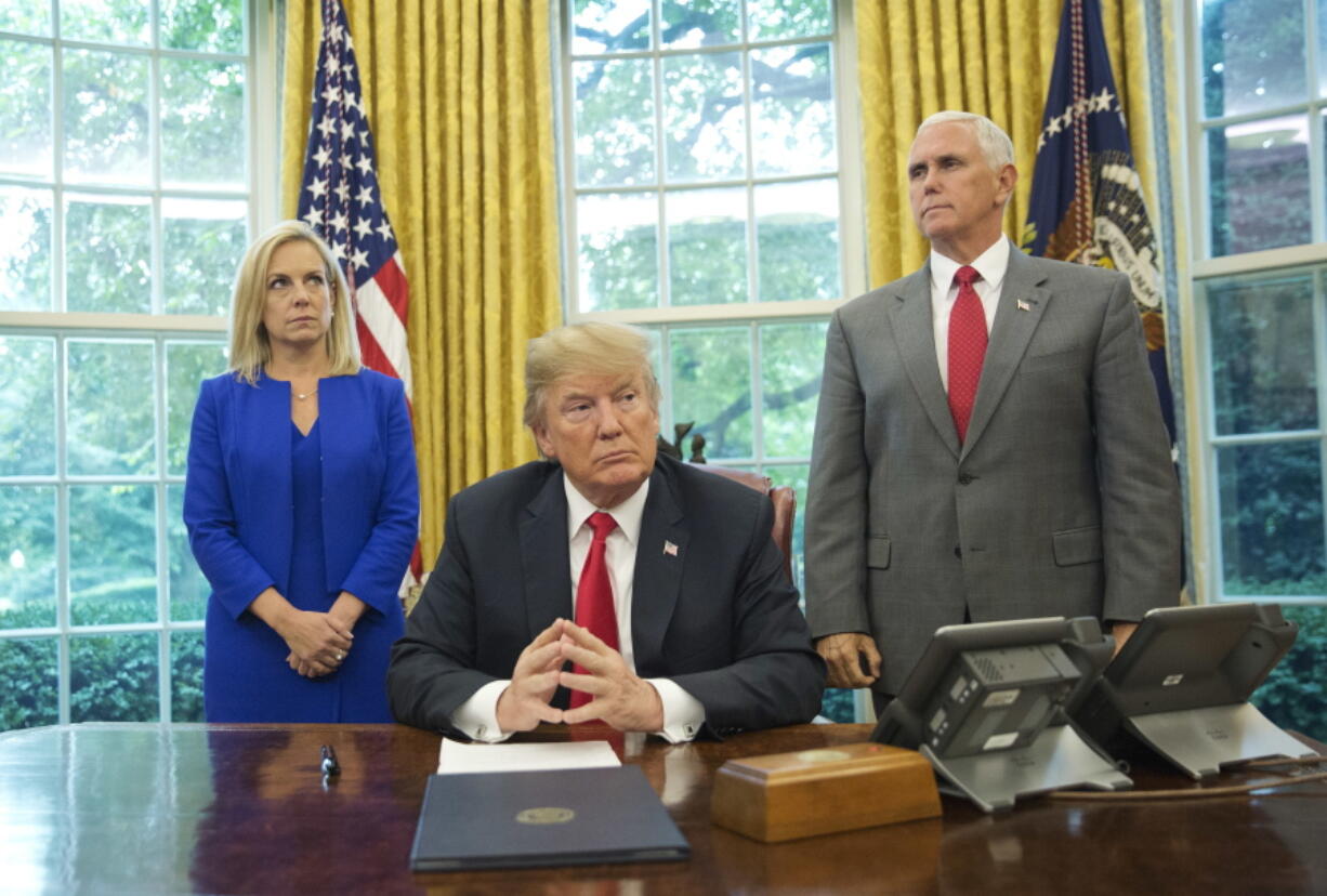 President Donald Trump, center, with Homeland Security Secretary Kirstjen Nielsen, left, and Vice President Mike Pence, right, before signing an executive order to end family separations, during an event in the Oval Office of the White House in Washington on Wednesday.