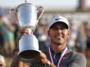 Brooks Koepka holds up the Golf Champion Trophy after winning the U.S. Open Golf Championship, Sunday, June 17, 2018, in Southampton, N.Y.