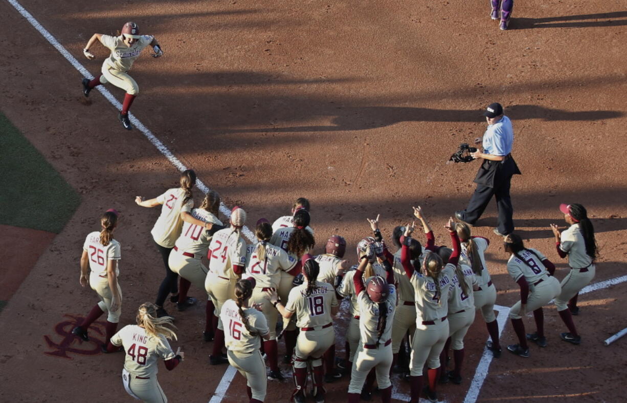 Florida State catcher Anna Shelnutt (13) celebrates her home run as she runs toward her teammates waiting at home plate in the first inning.