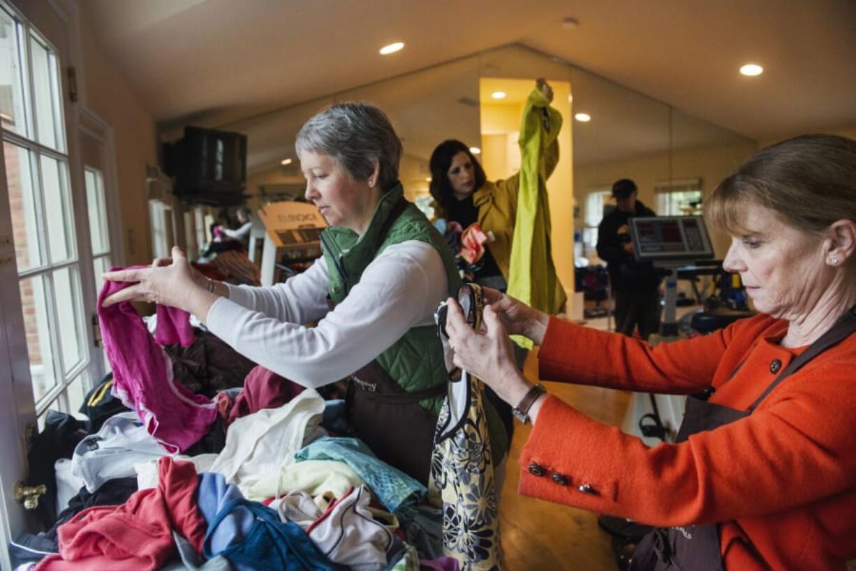 Lucie Holland, from left, Amy O’Donnell and Marian Bishop look through exercise clothing during an estate sale at the home of fitness guru Denise Austin on April 29, 2014, in Alexandria, VA.