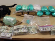 Clark County Sheriff’s Office drug canine, Piper, sits with a cache of drugs and cash seized in late June as part of an investigation into a drug trafficking organization.