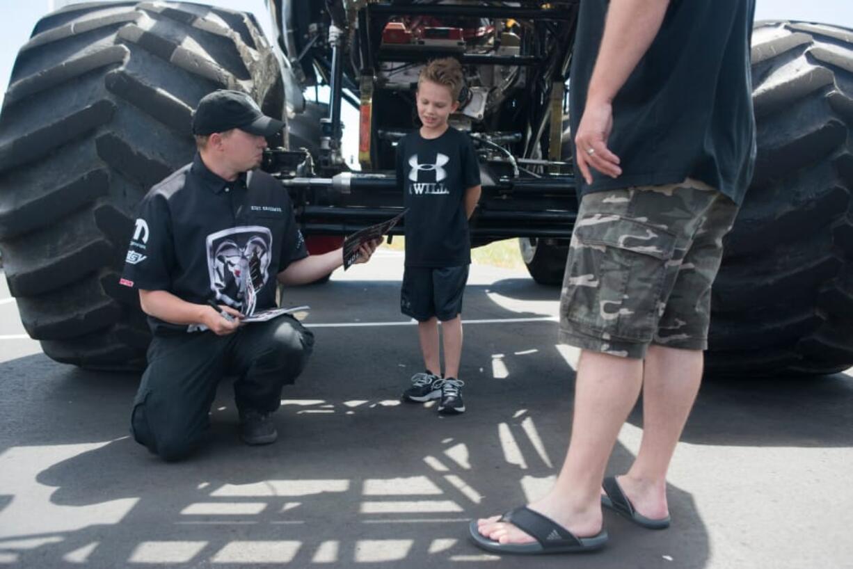 Raminator monster truck driver Kurt Kraehmer hands an autographed card to Tristan Wilcox, 6, at the Dick Hannah Ram Truck Center in Vancouver on Sunday. The Raminator was on display and crushed four cars during an exhibition at the dealership.