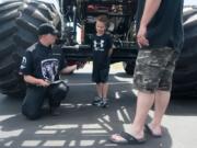 Raminator monster truck driver Kurt Kraehmer hands an autographed card to Tristan Wilcox, 6, at the Dick Hannah Ram Truck Center in Vancouver on Sunday. The Raminator was on display and crushed four cars during an exhibition at the dealership.