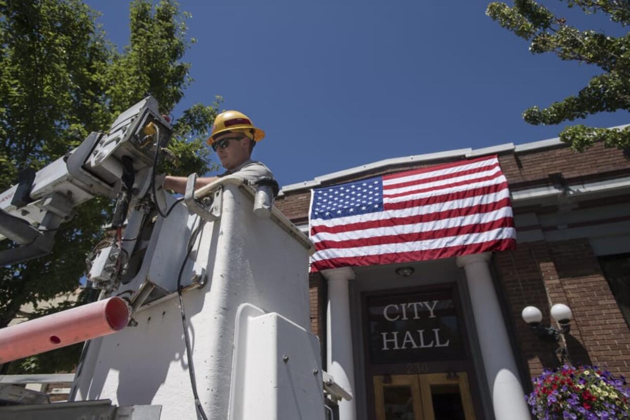 Spencer Kauffman, a facilities maintenance worker with the city of Ridgefield, helps secure the American flag outside City Hall on Tuesday afternoon in preparation for the upcoming Fourth of July parade. Kauffman, who said he planned to help out during the parade, said he was looking forward to the festivities and planned to watch fireworks with loved ones later in the evening.