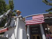 Spencer Kauffman, a facilities maintenance worker with the city of Ridgefield, helps secure the American flag outside City Hall on Tuesday afternoon in preparation for the upcoming Fourth of July parade. Kauffman, who said he planned to help out during the parade, said he was looking forward to the festivities and planned to watch fireworks with loved ones later in the evening.