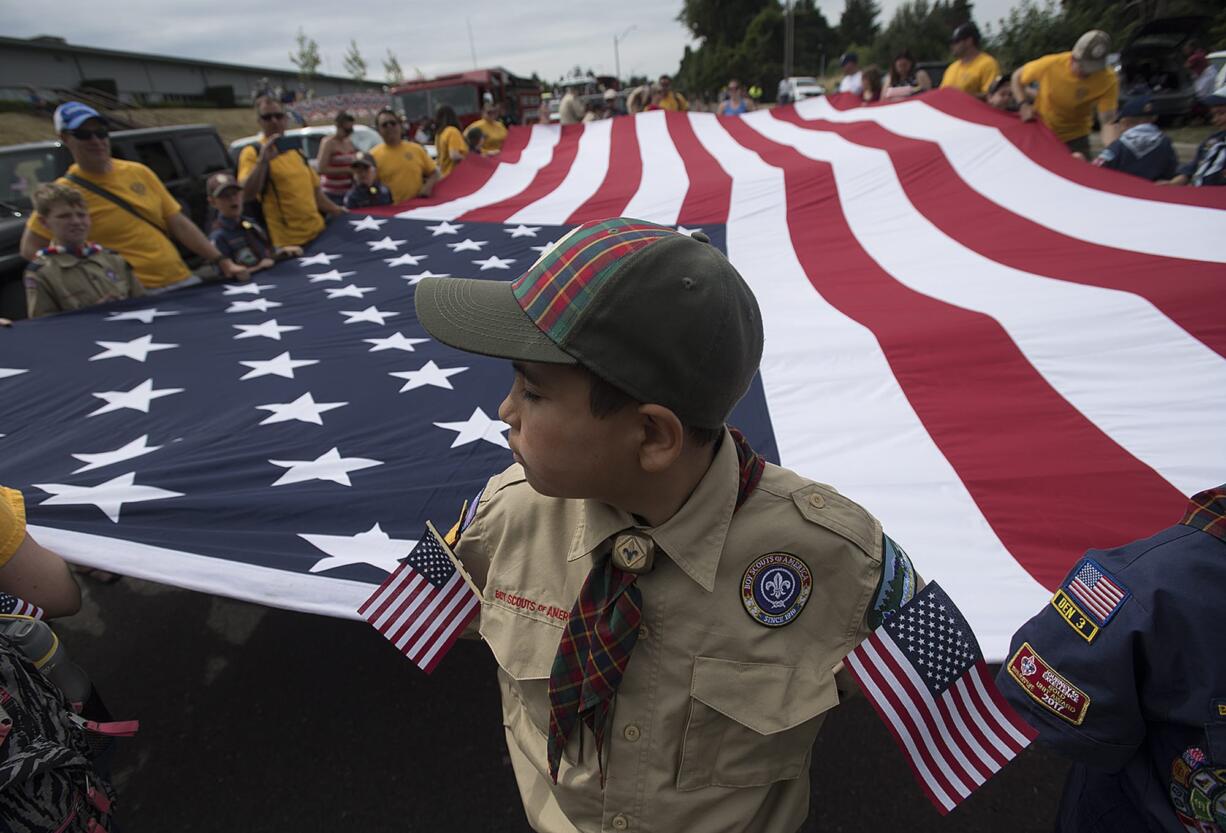 Ethan Dulay, 10, of Cub Scout Pack 310 of Ridgefield spends a quiet moment with the American flag while preparing for the start of the annual Ridgefield Fourth of July parade Wednesday morning. Dulay said this was his first year participating in the parade and said he was excited for the holiday. "I just like everything," he said. The theme of this year's parade was "Over There, Over There: 100 Years of the American Legion." The pack is chartered by the American Legion Post 44 in Ridgefield.