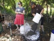 Volunteers Emily Bowen and Eric Stricker demonstrate how to properly manage a wire-bin style of compost container during Sunday’s Art in the Garden event at the Center for Agriculture, Science and Environmental Education in Brush Prairie.