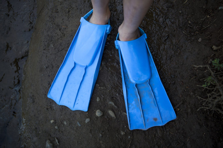 At top, Sydney Chamness of Gardnerville, Nev., sports a pair of flippers as she boards her family’s oversized paddle board at Lacamas Lake in Camas on Wednesday, July 11, 2018. Chamness and her family are in town visiting relatives for the week.