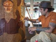 Yakama artist Toma Villa does some touch-up work Friday after repairing a crack in the wood in his Spirit Pole sculpture at the Fort Vancouver Visitor Center.