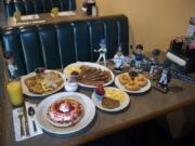 The offerings at Linda’s Homeplate include the half order of Linda’s Hash, from left clockwise, the French toast with bacon and scrambled eggs, homemade doughnuts with chocolate frosting, and the waffle with strawberries and whipped cream plus a side of eggs and a sausage patty.