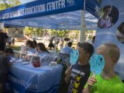 Vancouver residents Spencer Vincent, 8, second from right, and Allister Reilly, 9, right, pause to have their photo taken with the snake mask they colored Wednesday during Science in the Park at Esther Short Park.