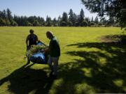 VINE Squad volunteers Tonya Baker, left, and her father Chuck Baker, both of Vancouver, carry a tarp filled with English ivy after pulling the plant from underneath trees during a cleanup event Thursday at LeRoy Haagen Memorial Community Park.