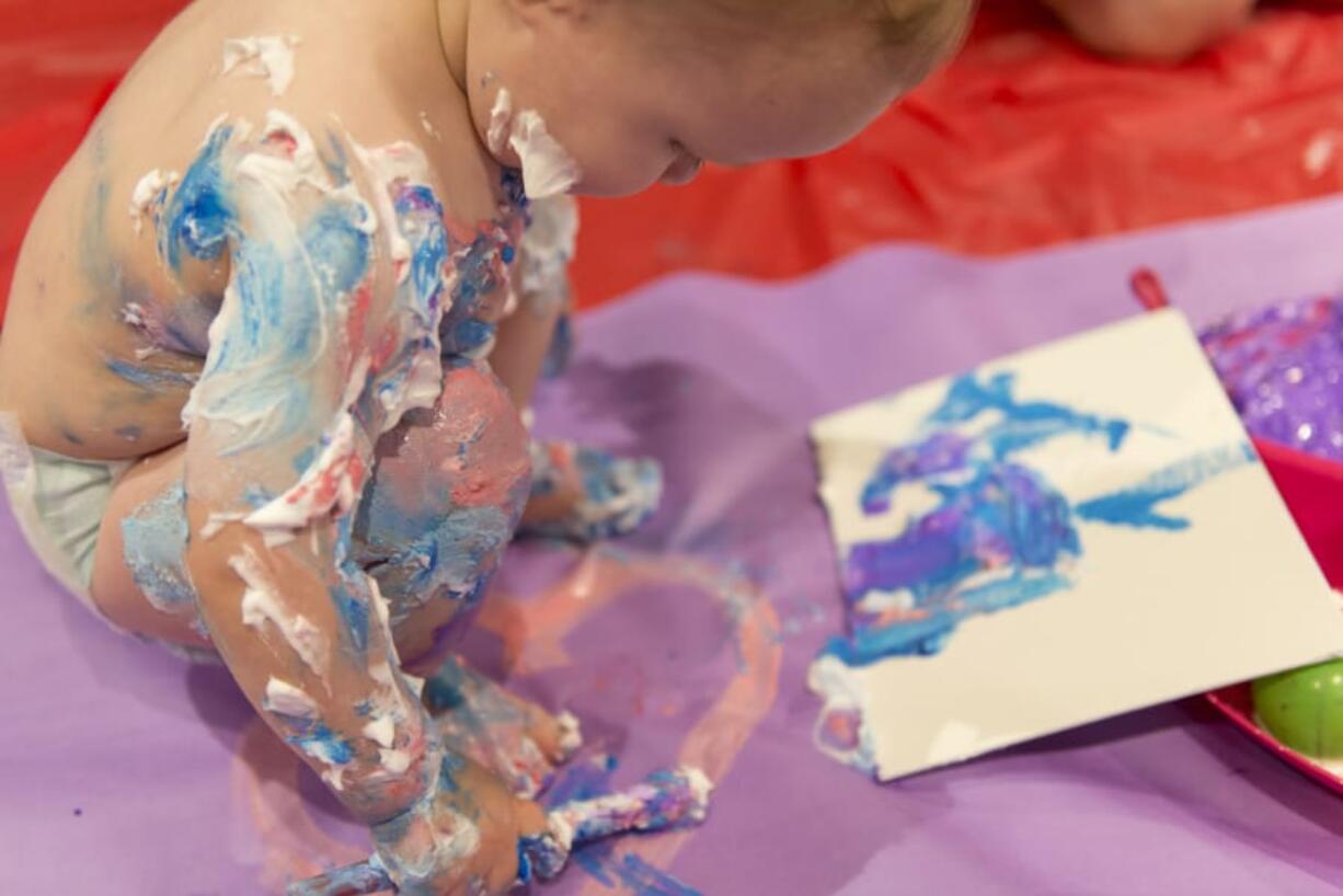 One-year-old Kellen Erwin plays with paints and shaving cream Sunday at Art ala Carte’s Messy Madness kids art event. The traveling arts event company lays out a big sheet for kids to work over as they explore with paints and brushes.