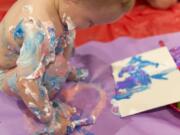 One-year-old Kellen Erwin plays with paints and shaving cream Sunday at Art ala Carte’s Messy Madness kids art event. The traveling arts event company lays out a big sheet for kids to work over as they explore with paints and brushes.