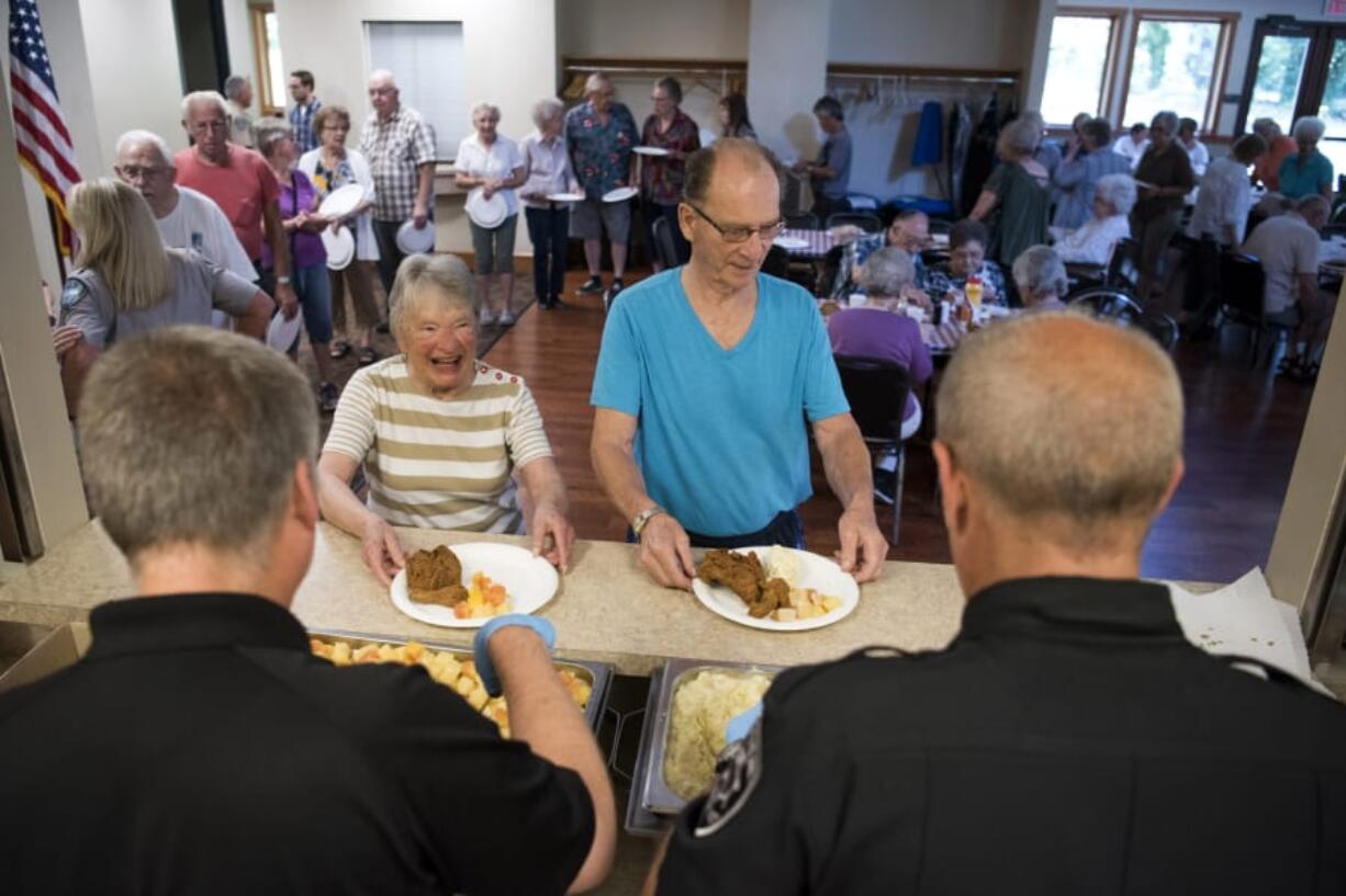 Faye Schanilec, back left, and her husband, Vern, back right, speak with Clark County Undersheriff Mike Cooke, front left, and Washougal Police Chief Ron Mitchell, front right, at SALT’s annual picnic at the Lacamas Lake Lodge in Camas on Monday. Vern said he enjoys connecting with local law enforcement in an informal setting. Below: Bob Hilberg of Vancouver digs intos a cupcake.