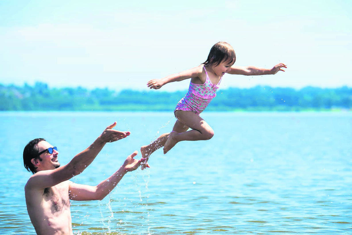 Bill Sherwin of Portland launches his daughter Nevella Sherwin, 4, into the air while swimming at Vancouver Lake in July.