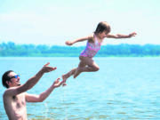 Bill Sherwin of Portland launches his daughter Nevella Sherwin, 4, into the air while swimming at Vancouver Lake in July.