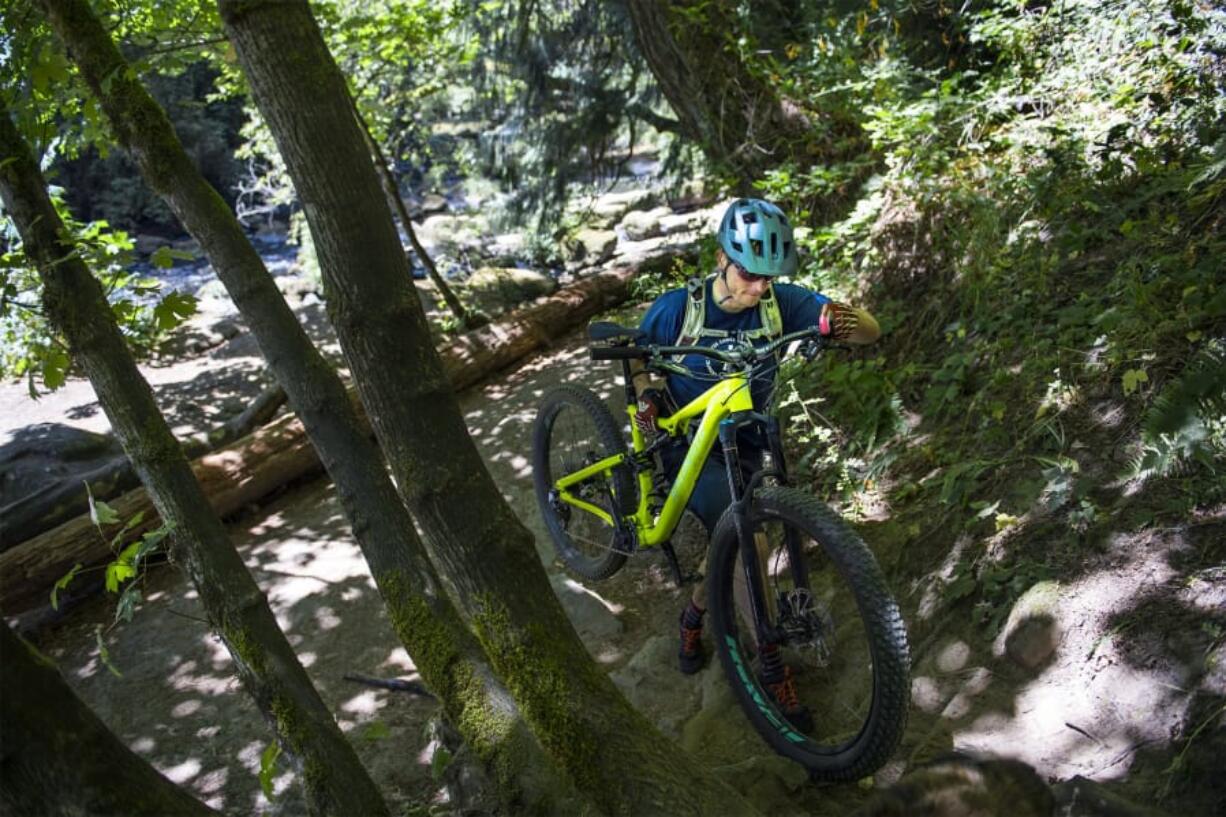 Scott McClelland of Portland carries his bike up an incline near the intersection of Lacamas McEnry and Red Tape trails in Lacamas Regional Park. Clark County Parks has designated the Red Tape trail as a bikes-only route, the first of its kind in the Clark County park system.