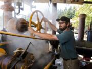 Ryan Johnson, of Amboy, operates a turn of the century Corliss steam engine Sunday at the Iron Ranch Antique Tractor, Engine Show and Flea Market in Ridgefield. The 600-horsepower steam engine once powered an entire sawmill in northern Washington.