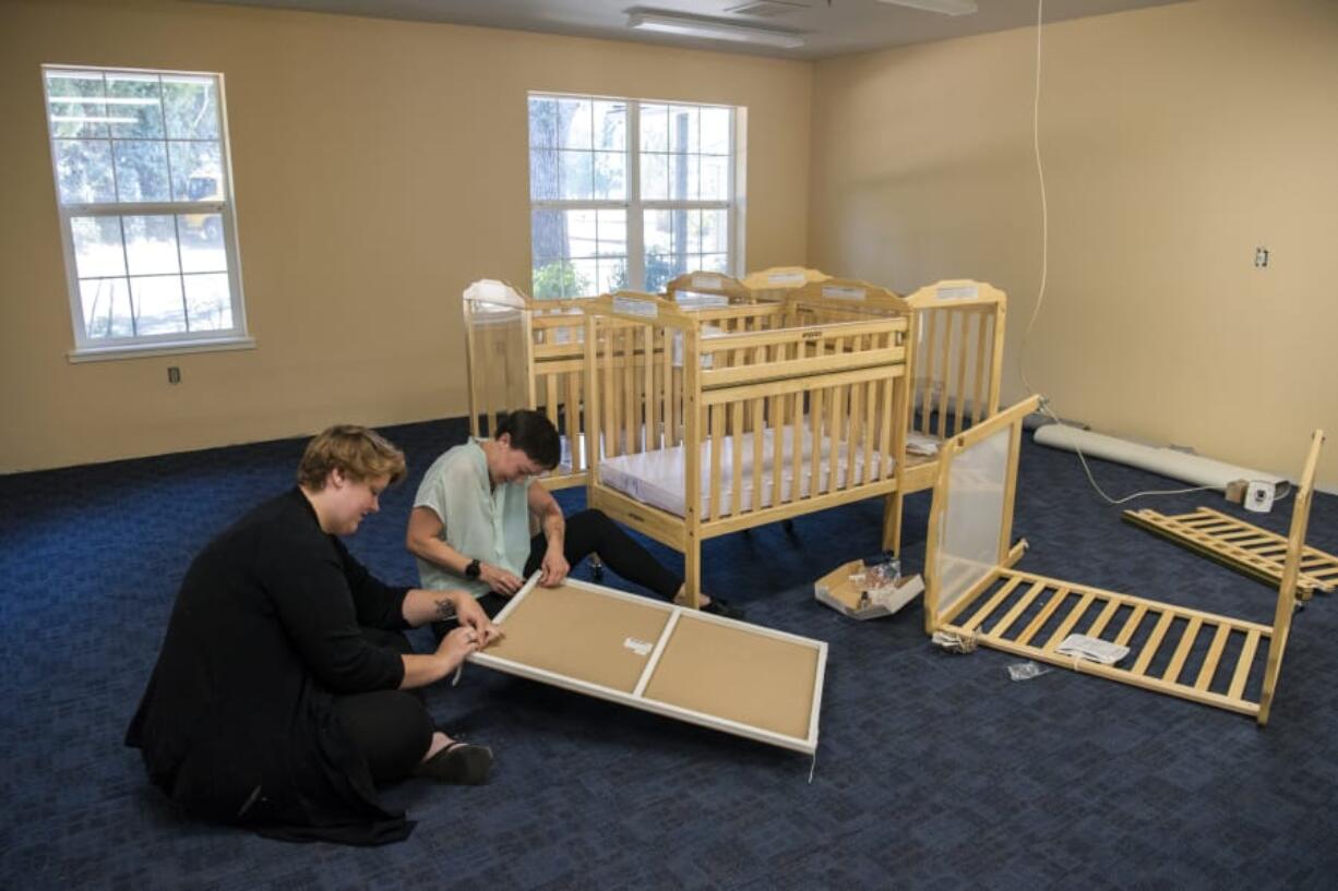 Infant teacher Breanna Levesque, left, and child care supervisor Trista Dunford put together cribs for the Pregnant and Parenting Women’s Program at the Women’s Recovery Center in Vancouver on Tuesday.