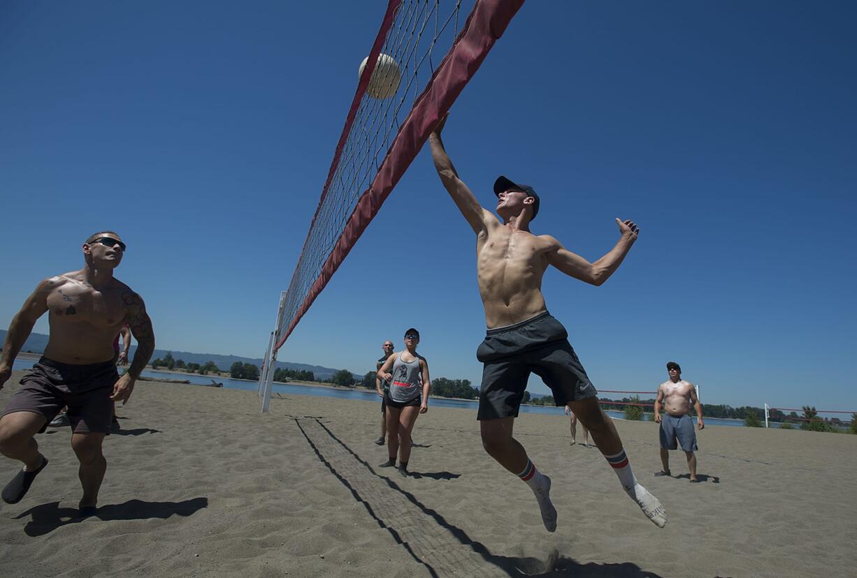 Michael Erickson, 16, of Vancouver, right, charges the net while playing a friendly pick-up volleyball game with family and friends at Frenchman's Bar Regional Park on Monday afternoon. Erickson said he planned to escape the heat and cool off in the nearby water following the game.