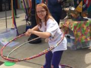 Battle Ground: Brynlee Hammond testing her hula hoop skills at Summertime YUM! booth at the Battle Ground Farmers Market. Washington State University Extension is traveling around to farmers markets this summer to go over health tips.