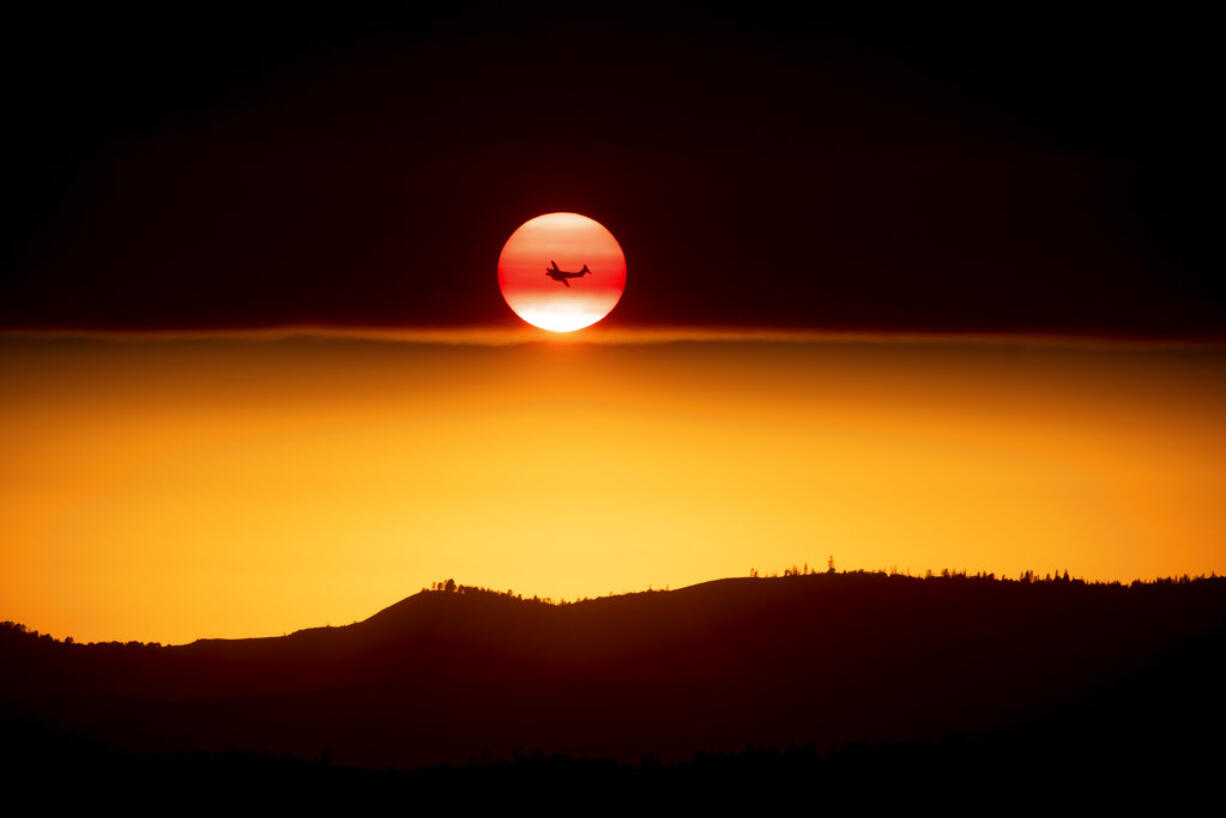 A plane battling the Ferguson Fire passes the setting sun in unincorporated Mariposa County Calif., near Yosemite National Park on Sunday, July 15, 2018.