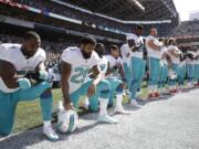 Miami Dolphins' Jelani Jenkins, Arian Foster, Michael Thomas, and Kenny Stills, kneel during the singing of the national anthem before a game against the Seattle Seahawks last season.