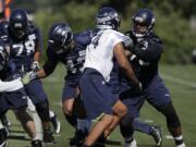 Seattle Seahawks' offensive tackle Duane Brown, right, takes part in a drill with linebacker Marcus Smith, second from right, during NFL football training camp, Thursday, July 26, 2018, in Renton, Wash. (AP Photo/Ted S.