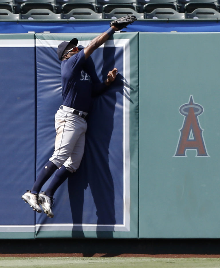 Seattle Mariners left fielder Denard Span leaps at the fence to catch Los Angeles Angels' Andrelton Simmons RBI sacrifice fly ball, to score Justin Upton, during the seventh inning of a baseball game in Anaheim, Calif., Sunday, July 29, 2018.